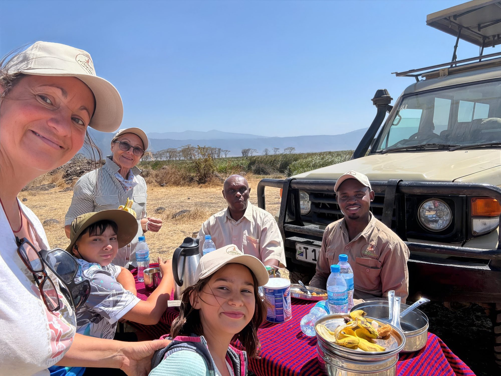 Gäste und Guides beim Picknick neben dem Safarifahrzeug