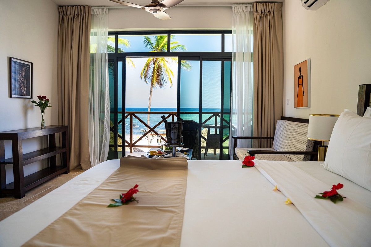 Zimmer mit Bett und Meerblick durchs Fenster