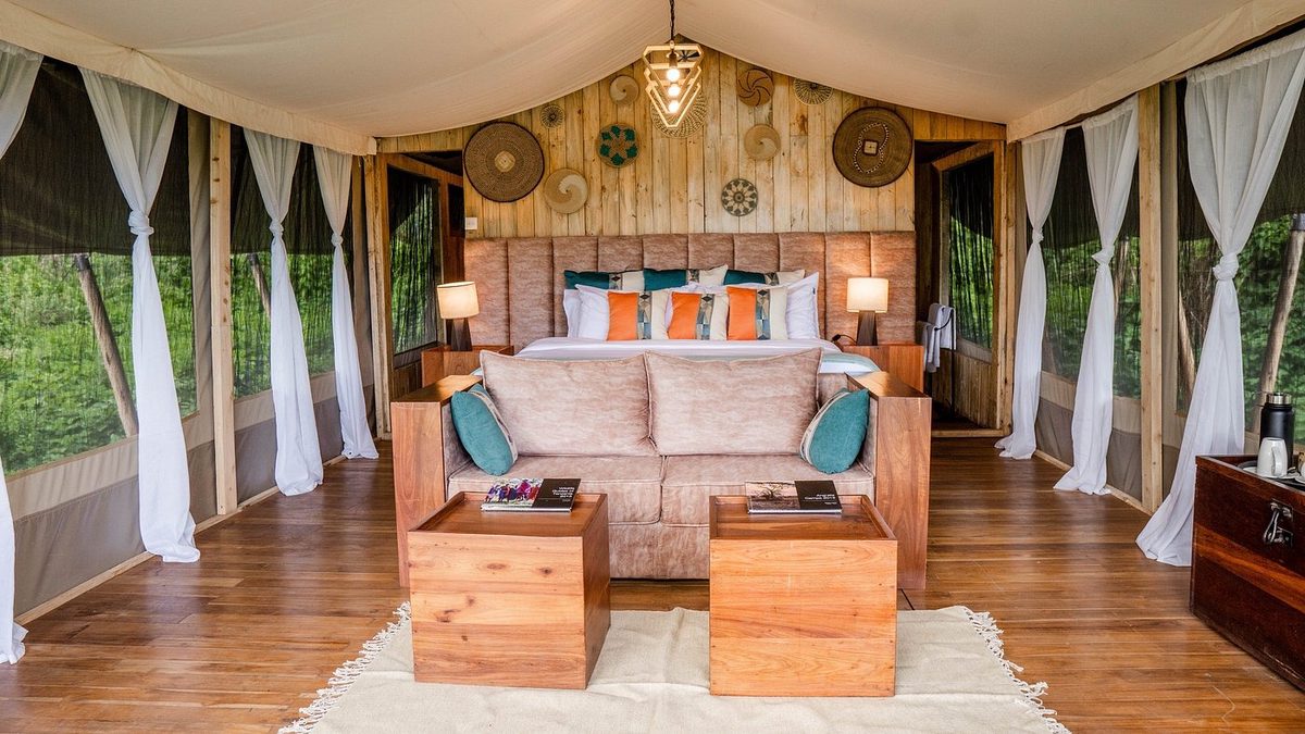 Zeltzimmer mit Bett, Holzboden und warmer Deko
