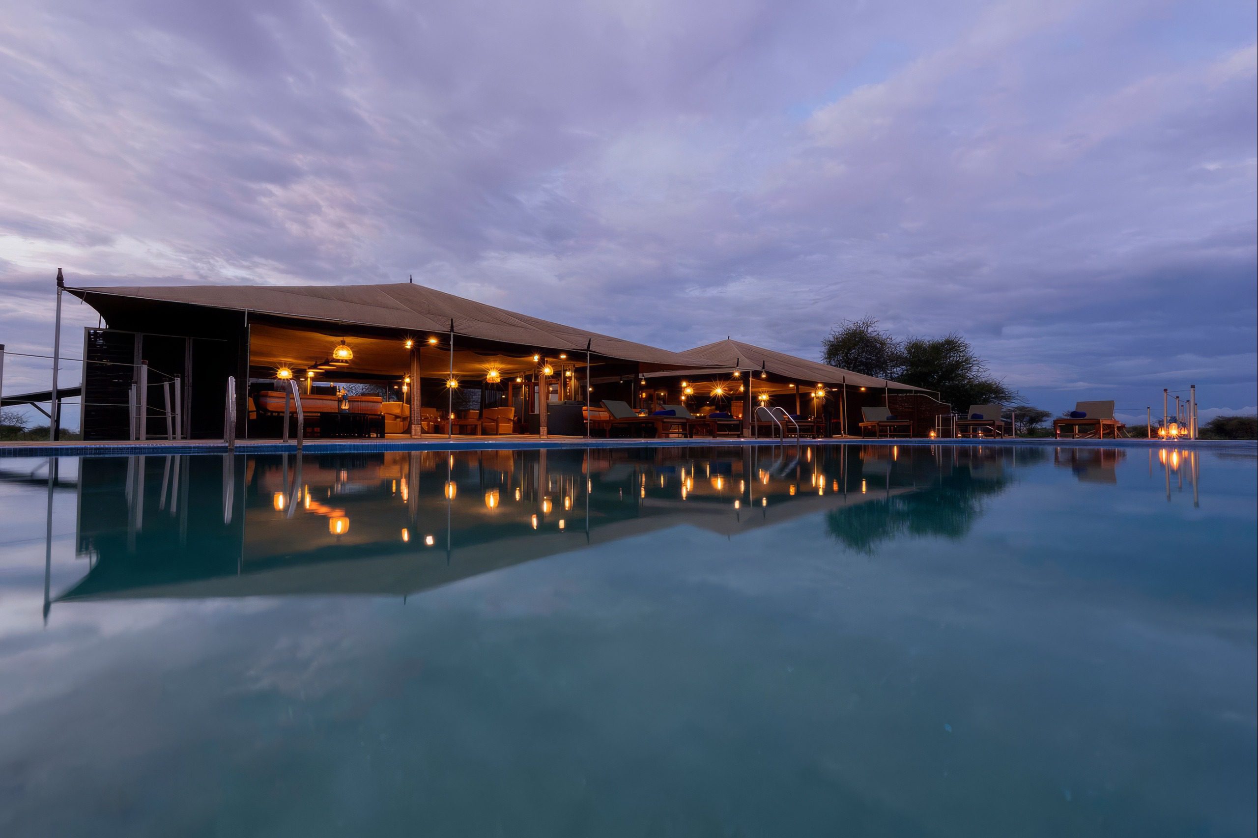 Beleuchteter Pool des Arukore Simba Camp Serengeti bei Abenddämmerung