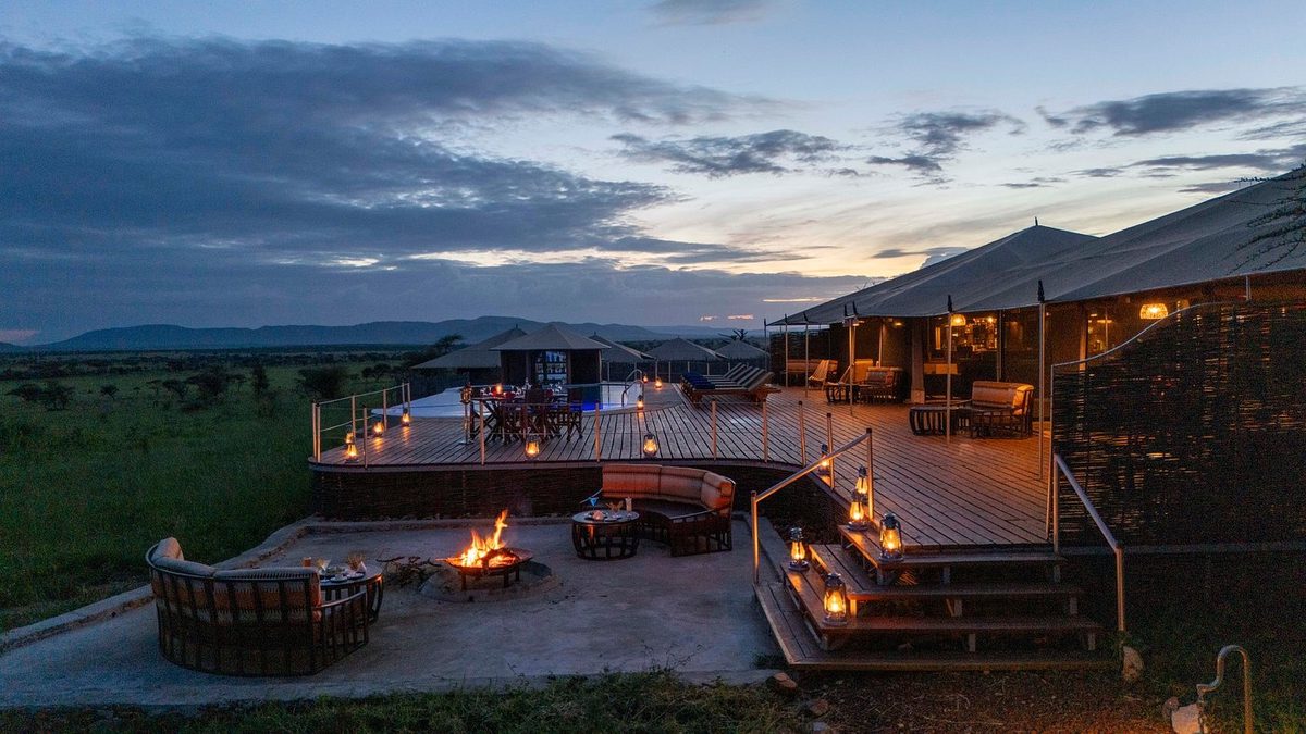 Terrasse mit Feuerstelle und Zeltreihe bei Dämmerung