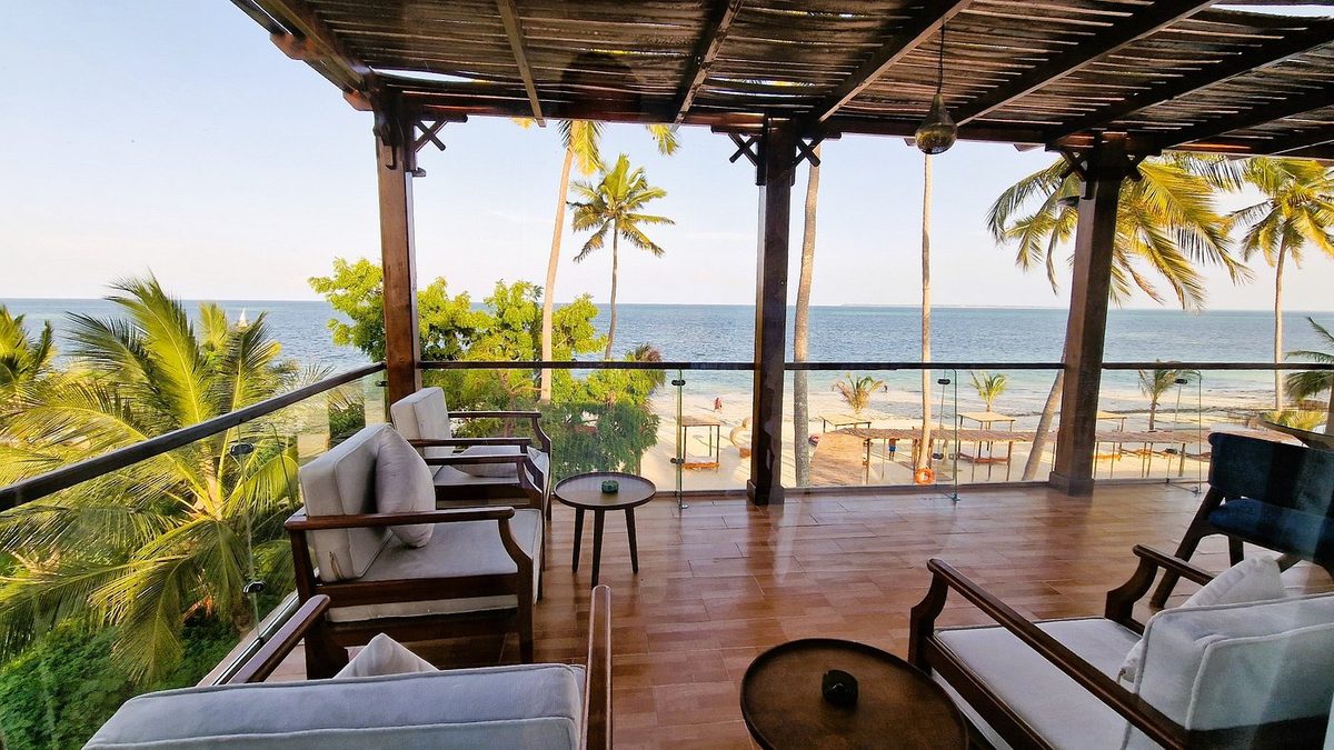 Überdachte Terrasse mit Sitzmöbeln, Palmen und Meerblick