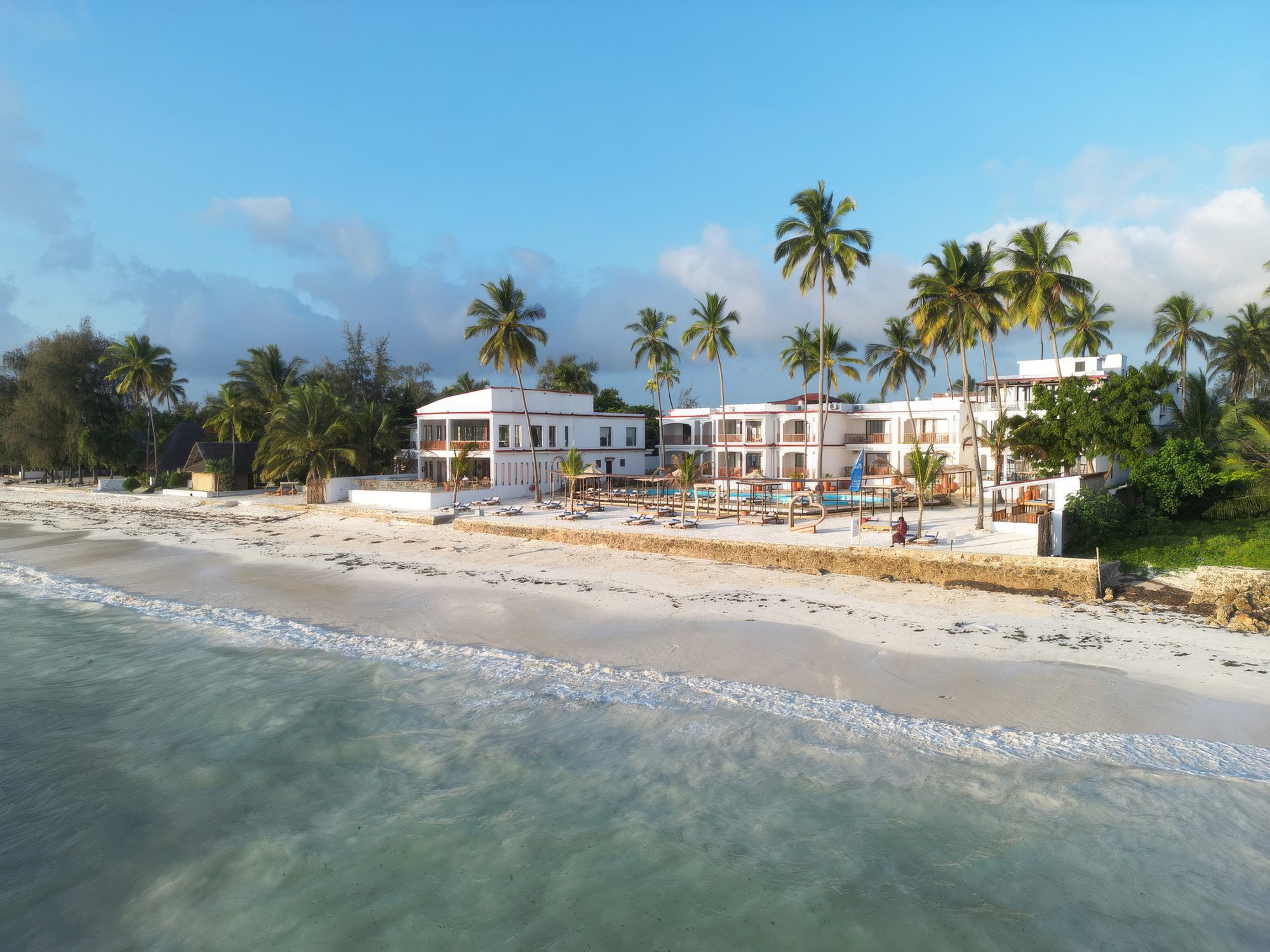 Edificio de Dream of Zanzibar en la playa con palmeras y mar turquesa