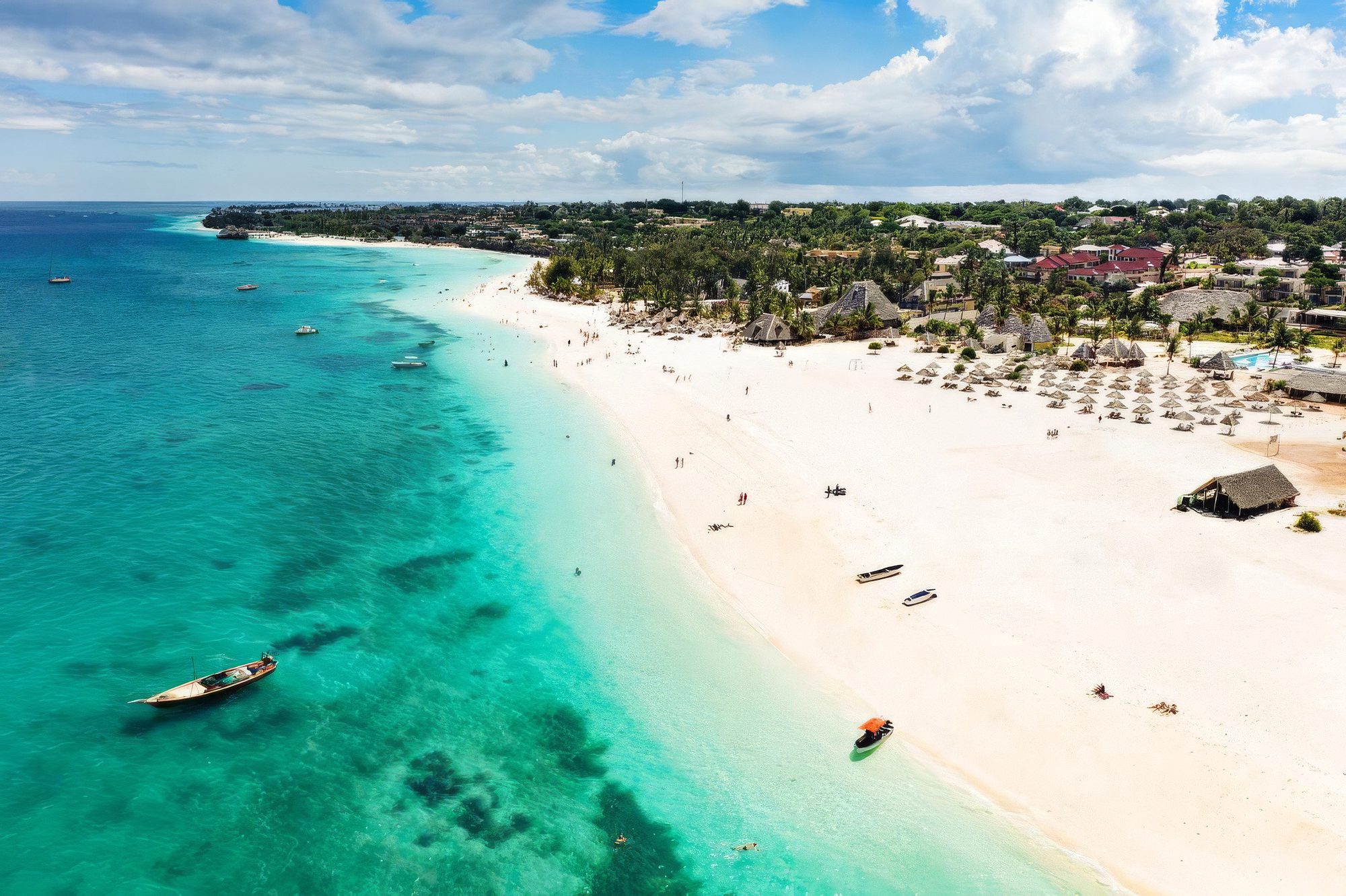 Playa de arena con barcas y mar turquesa en el Gold Zanzibar Beach House & Spa