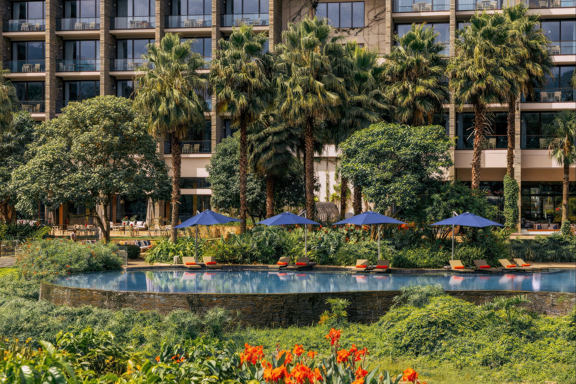 Pool des Gran Meliá in Arusha zwischen Palmen und Hotelgebäude