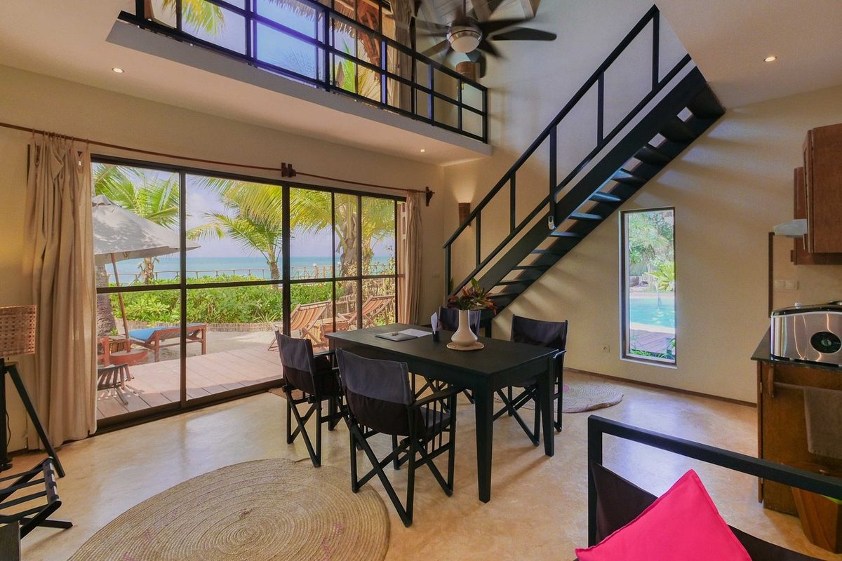 Zona de estar interior con galería y mesa de comedor