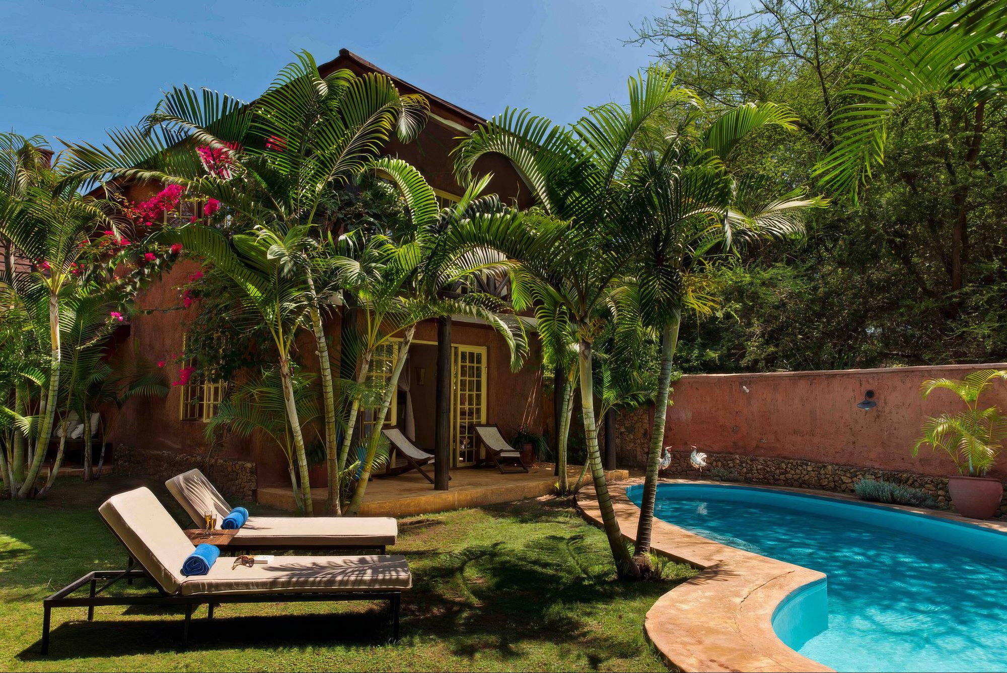 Jardín de la Kili Villa con piscina, tumbonas y palmeras