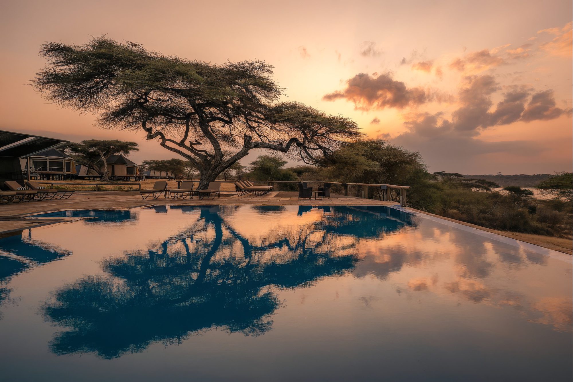 Piscina de la Lake Masek Luxury Tented Lodge a la puesta de sol con el reflejo de un árbol