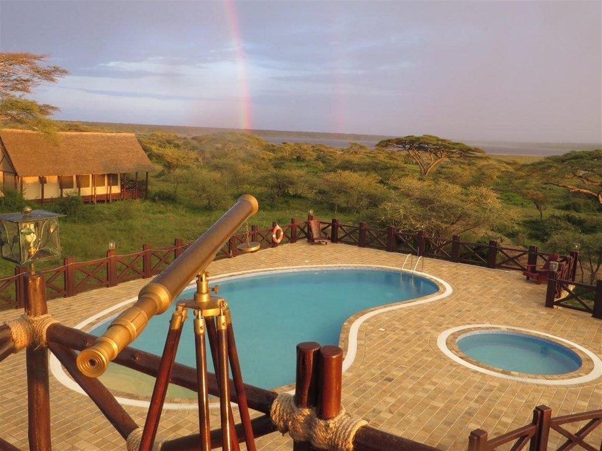 Pool-Terrasse mit Fernrohr und Regenbogen über der Savanne