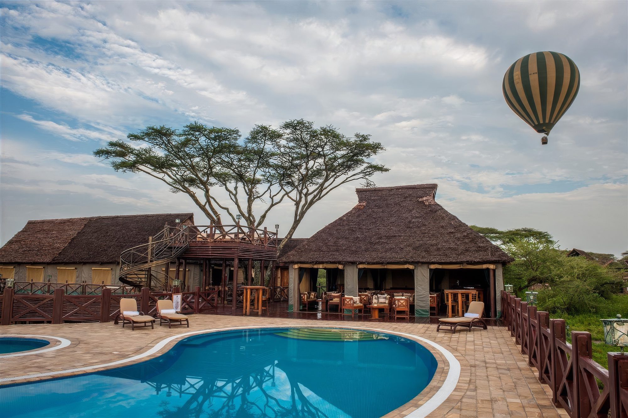 Pool-Terrasse der Lake Ndutu Luxury Tented Lodge mit Heißluftballon am Himmel