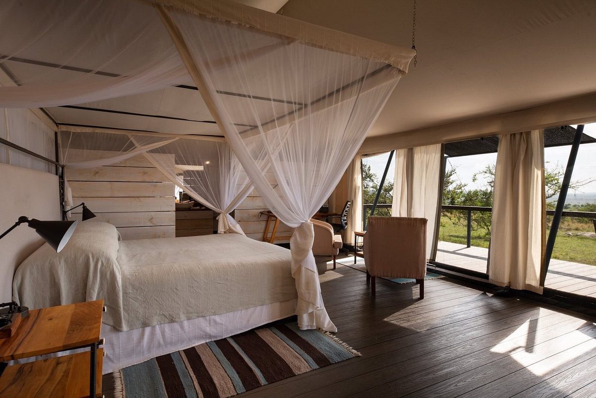 Tented room with bed, mosquito net and terrace views