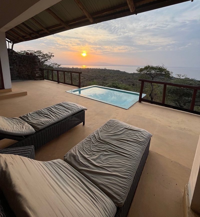 Überdachte Terrasse mit Pool und Landschaftsblick bei Sonnenuntergang