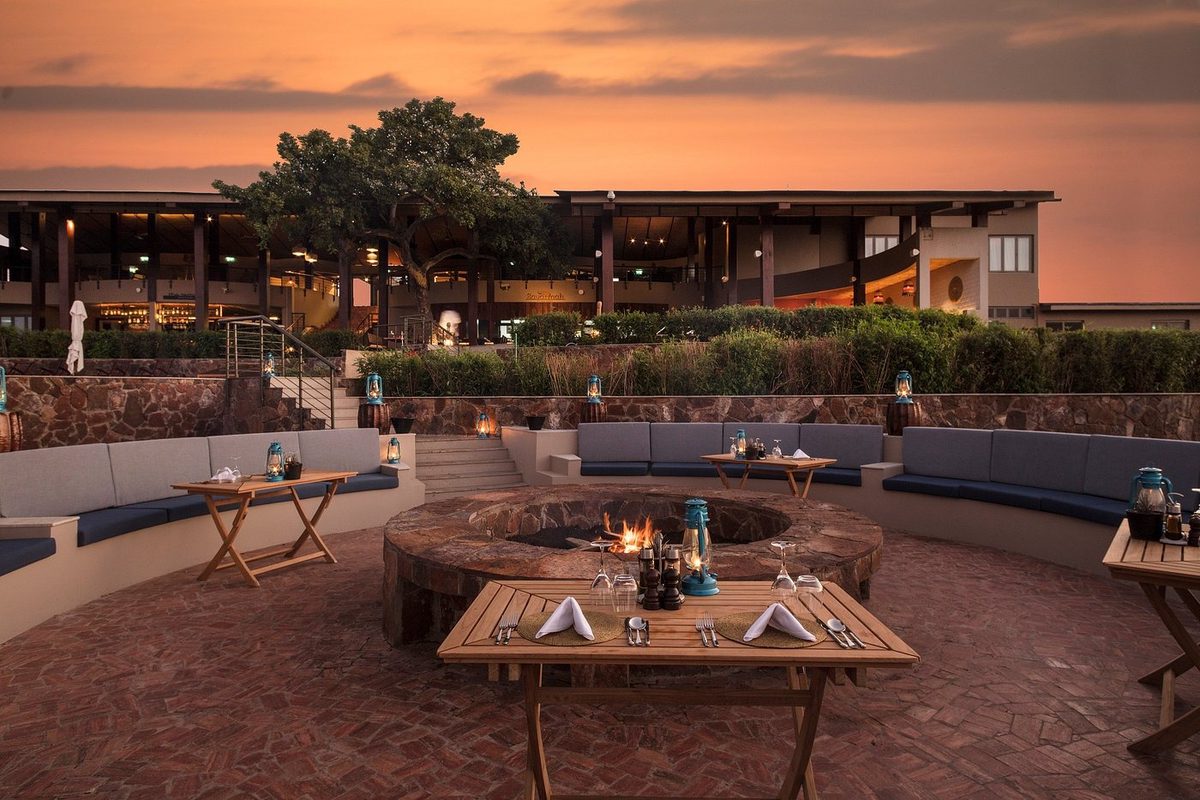 Terrasse mit Feuerstelle und Sitzmöbeln bei Sonnenuntergang