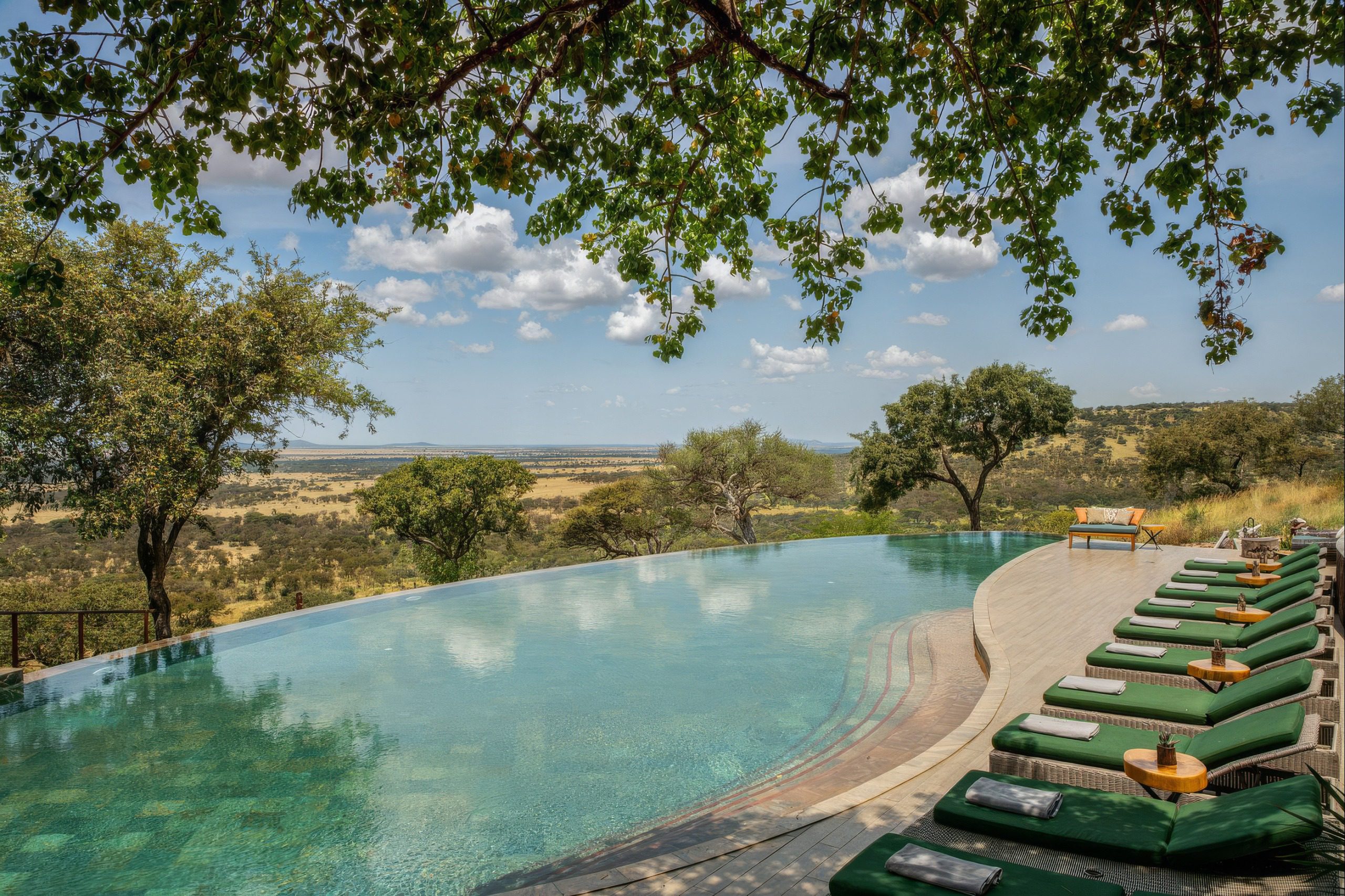 Pool der Meliá Serengeti Lodge mit Liegen und Blick über die Savanne