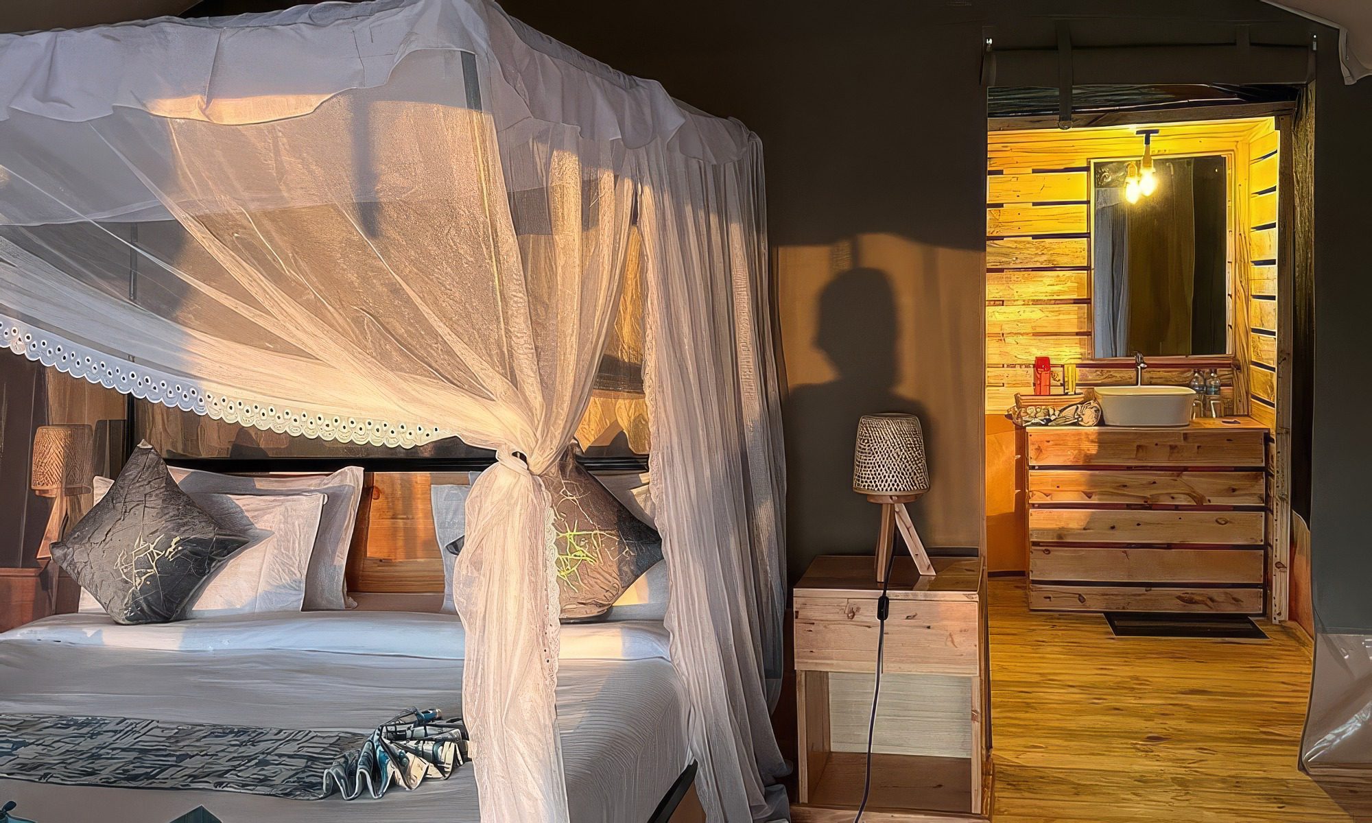 Inside a tent: bed with a mosquito net and wooden furniture