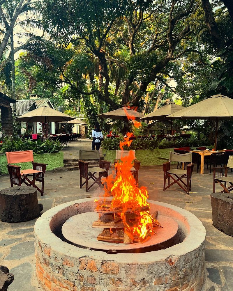 Garten mit Feuerstelle und überdachtem Sitzbereich im Hintergrund