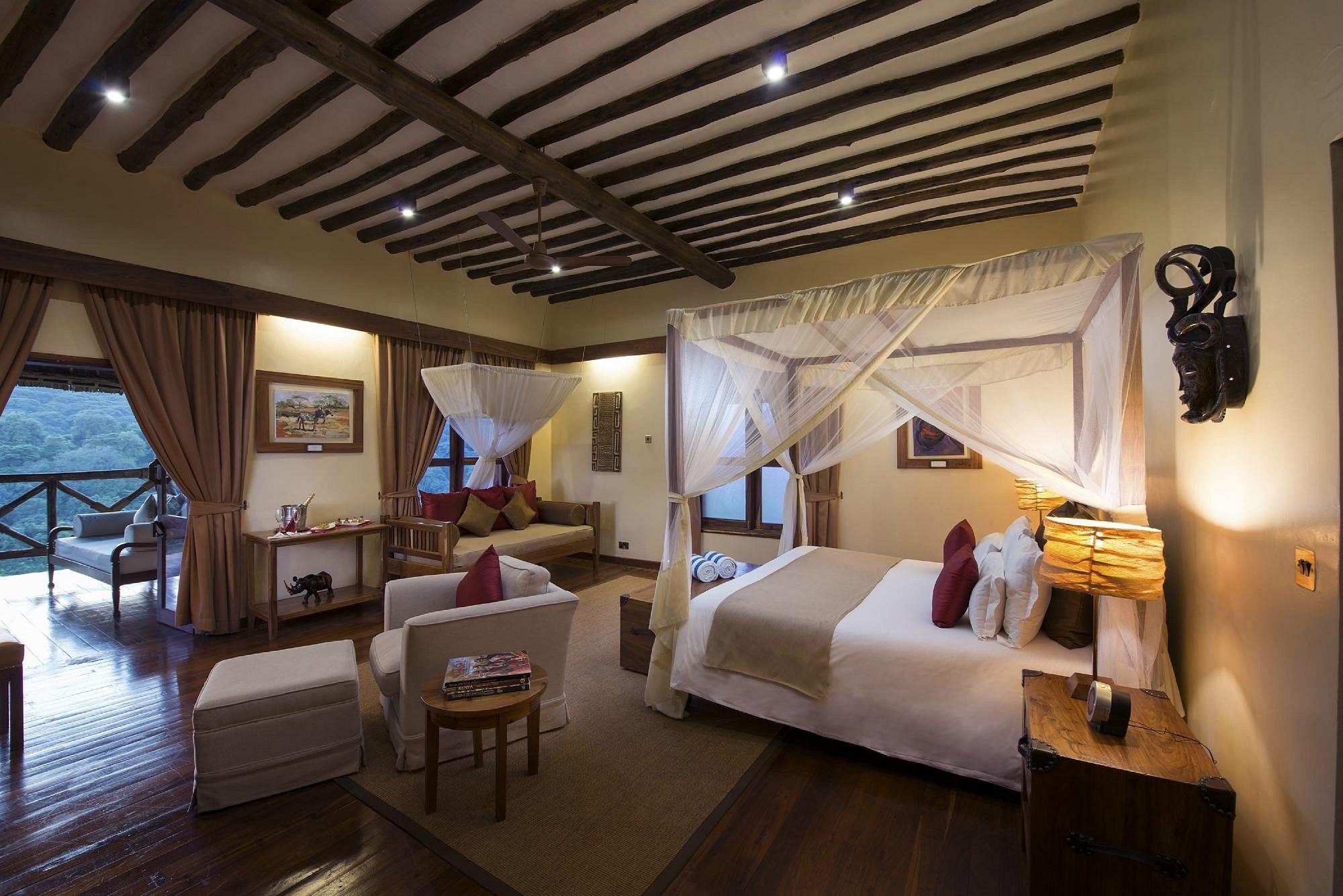 Interior de habitación con cama con mosquitera y rincón de asientos