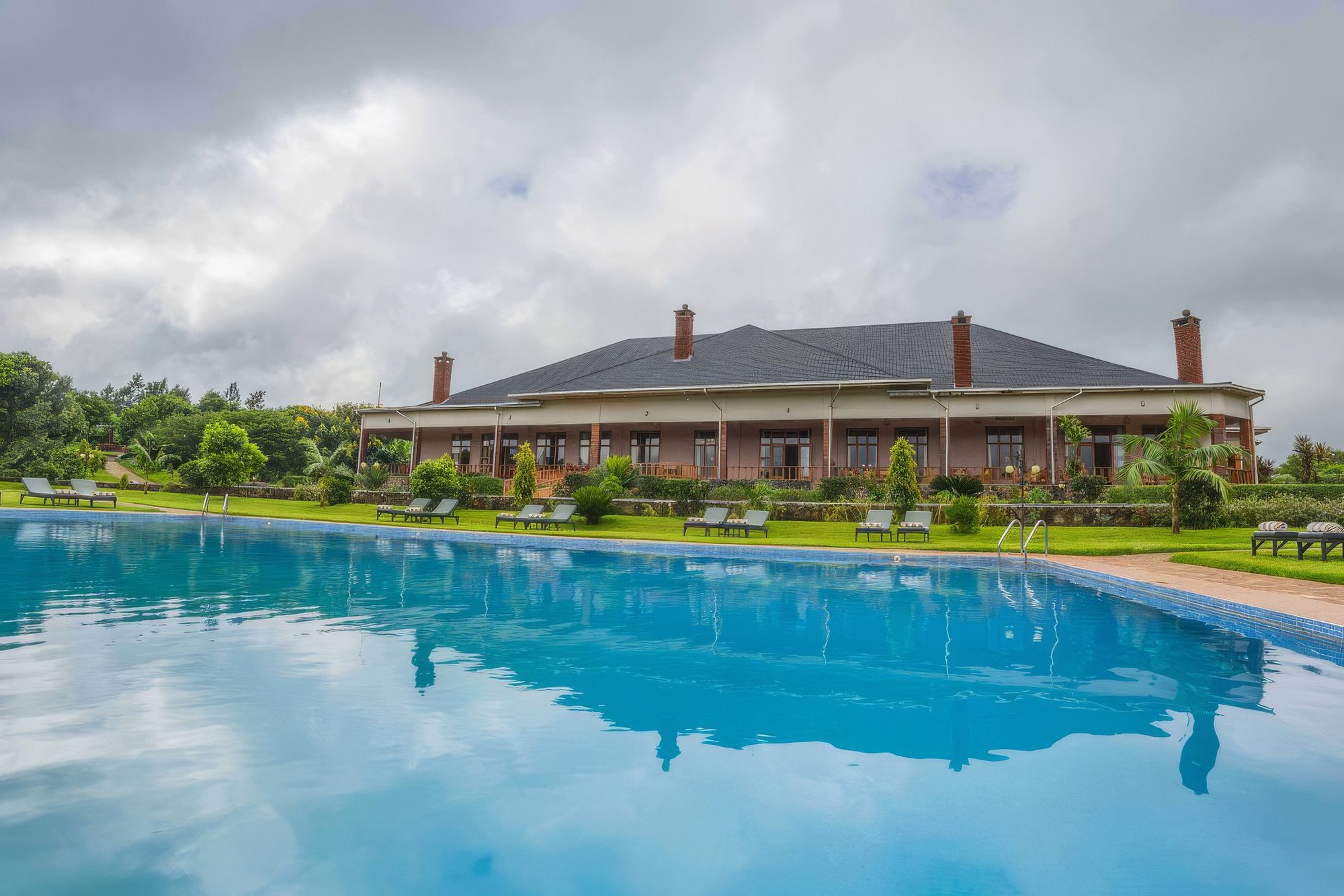 Gebäude der Ngorongoro Coffee Lodge mit Pool und Rasenfläche