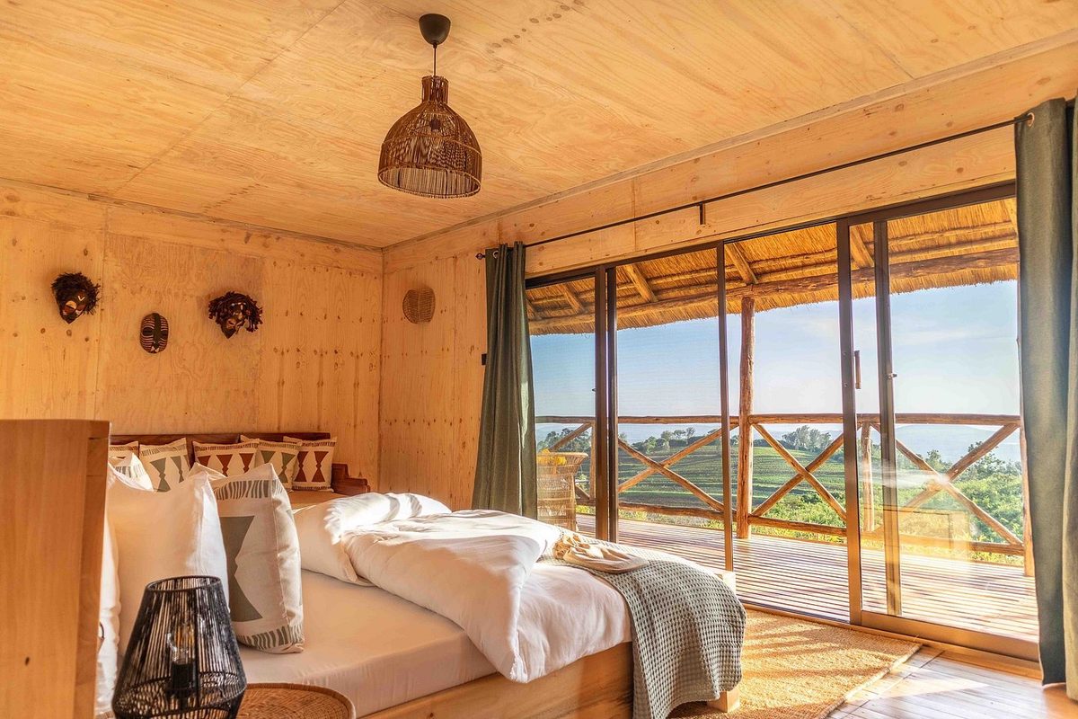 Zimmer mit Bett, Panoramafenster und Blick in die Landschaft