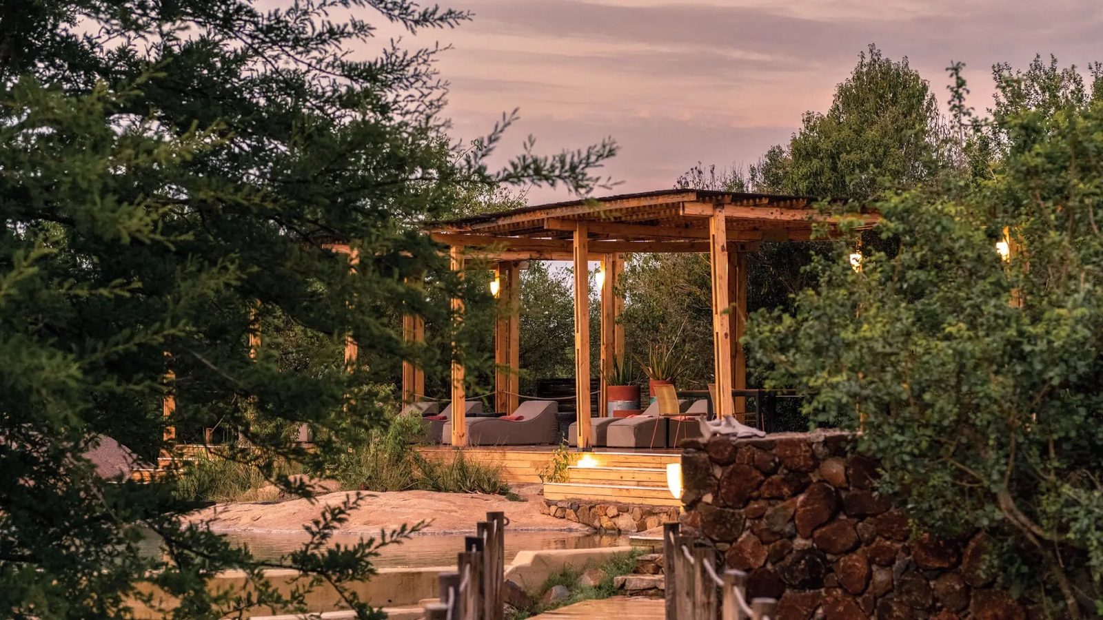 Covered terrace with seating furniture between rocks at dusk