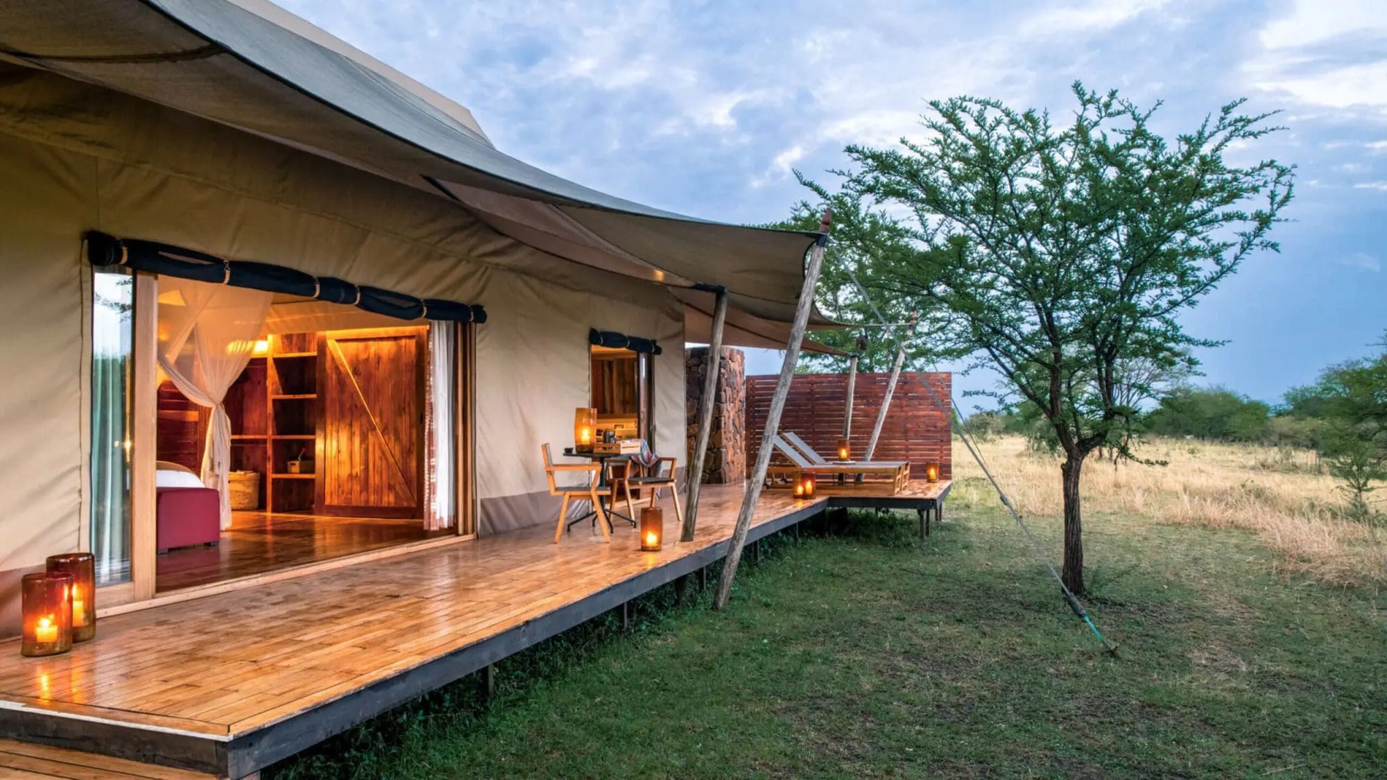 Interior of a tent room with views of the terrace at dusk