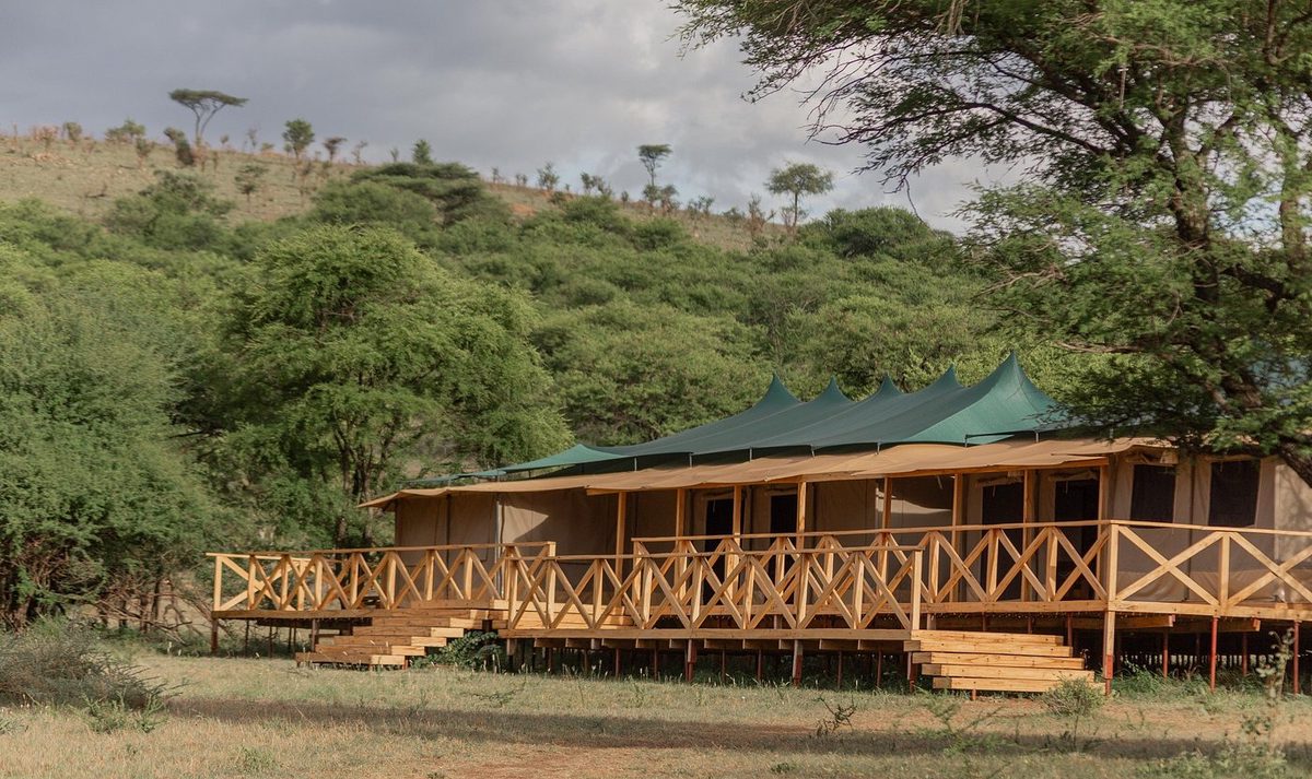 Tented lodge on the hillside in green landscape