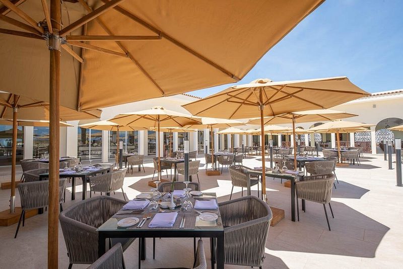 Überdachte Terrasse mit Sonnenschirmen und gedeckten Tischen