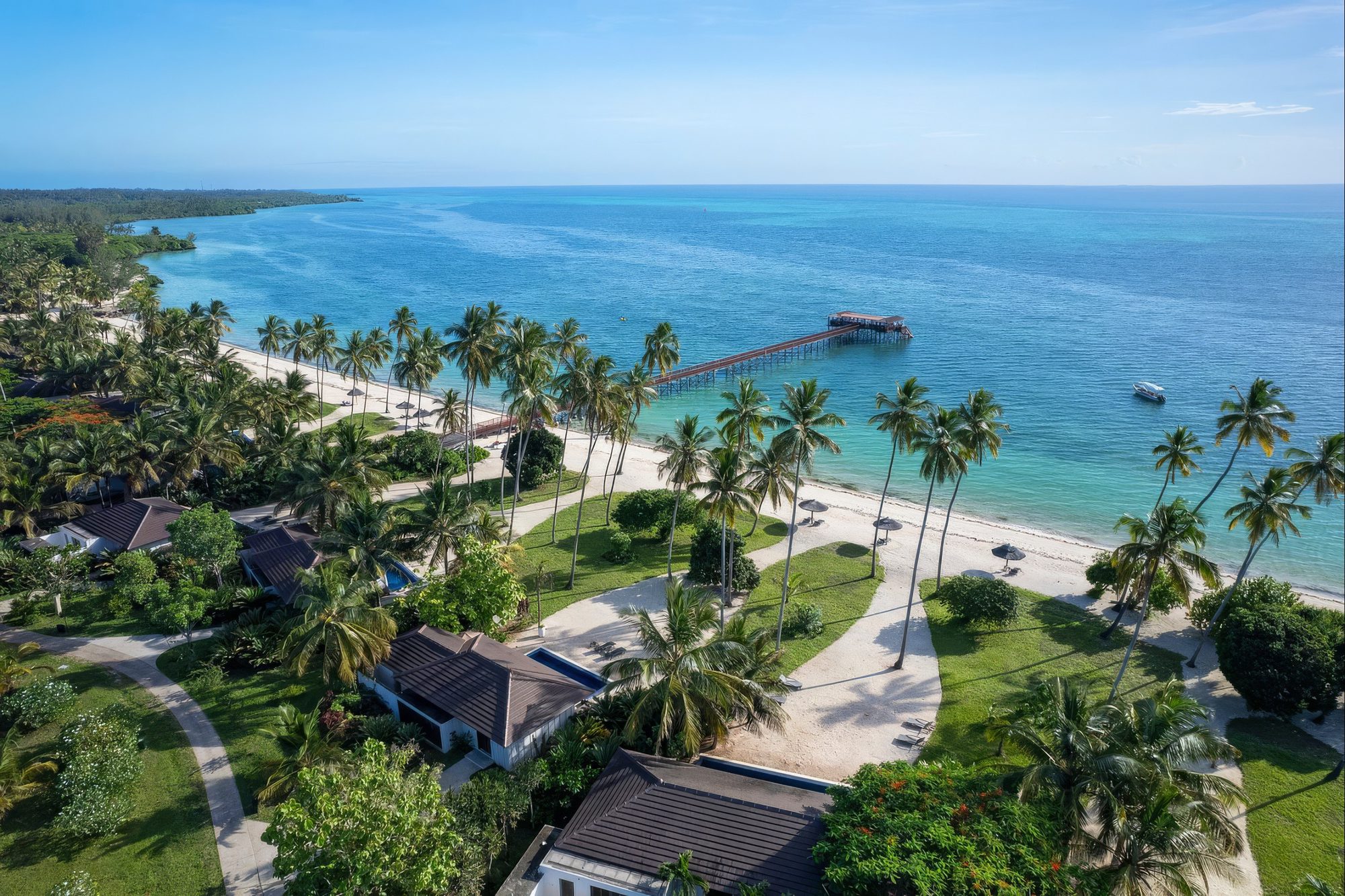 Complejo de The Residence Zanzibar en la playa con pasarela y palmeras