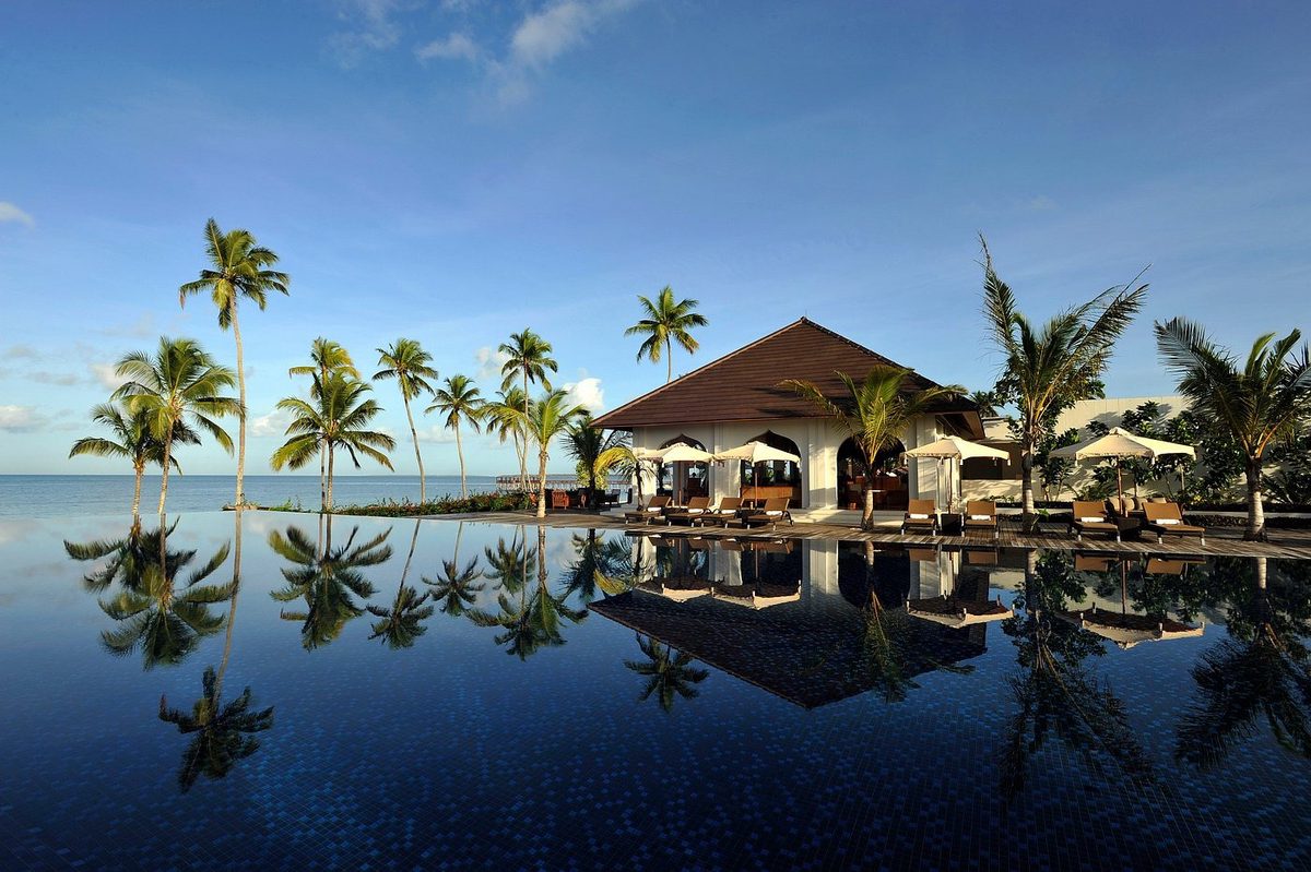 Pool mit Palmenspiegelung und Gebäude im Hintergrund