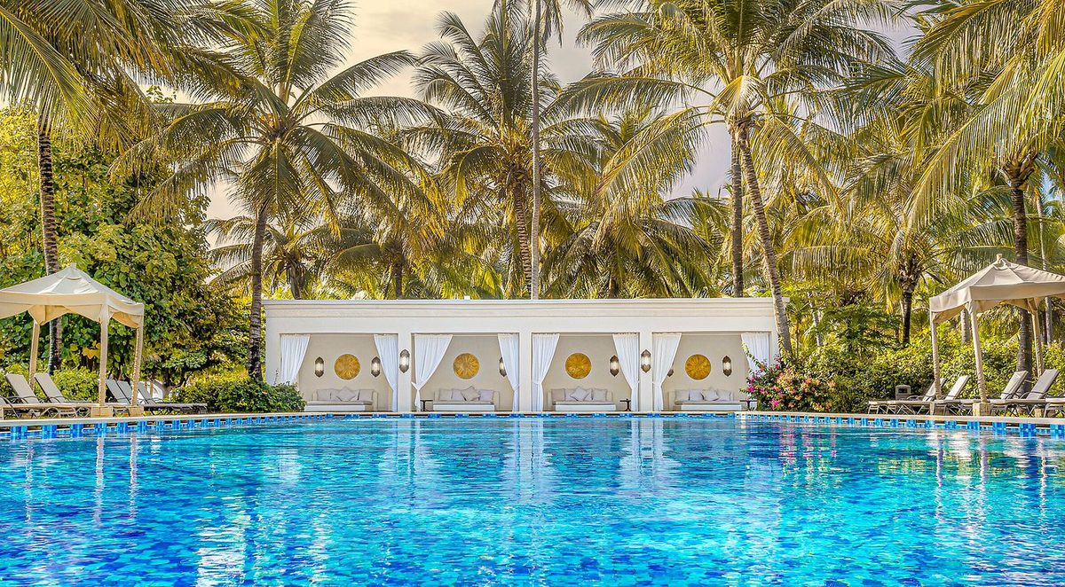 Gran piscina del Baraza Resort & Spa Zanzibar con pabellones blancos y tumbonas bajo palmeras