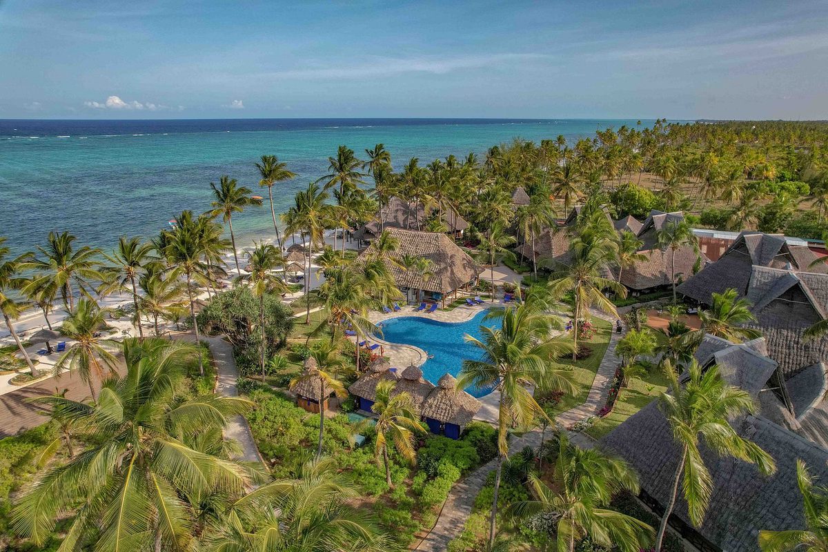 Complejo del Breezes Beach Club & Spa con edificios de techo de paja y piscina entre palmeras en la playa