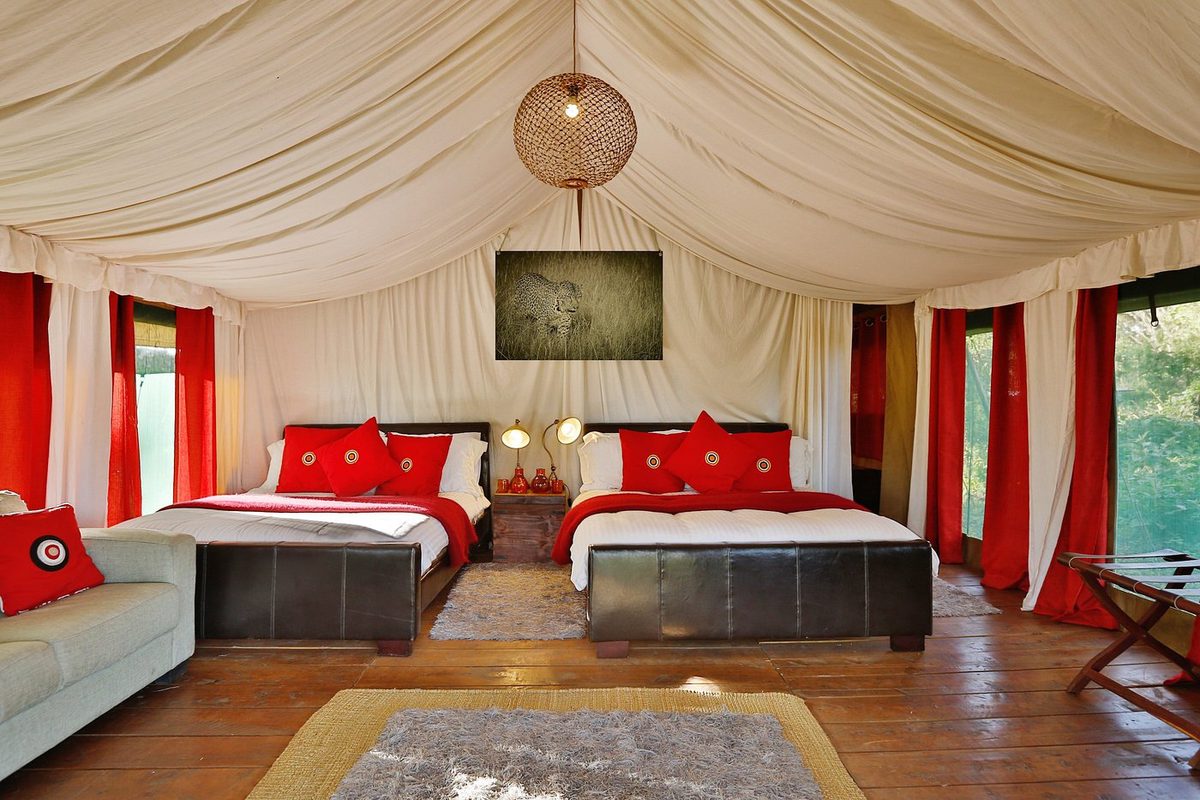 Zeltzimmer im Lemala Ngorongoro Tented Camp mit zwei Doppelbetten, roten Kissen und roten Vorhängen