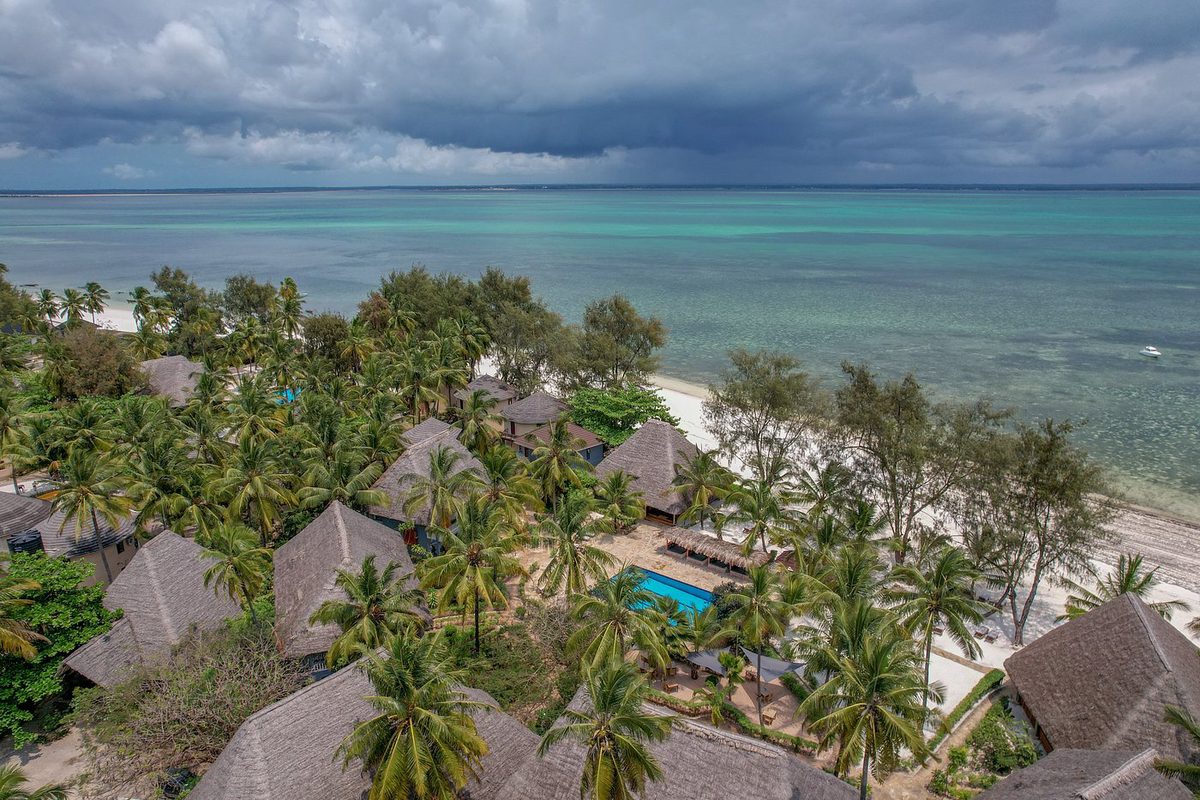 Vista aérea de los bungalows con techo de paja de la Michamvi Sunset Bay entre palmeras en la playa