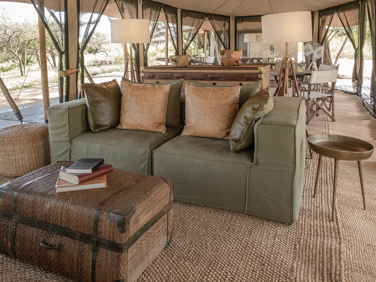 Lounge-Zelt im Mila Tented Camp mit grünem Sofa, Kofferhocker und Lampen