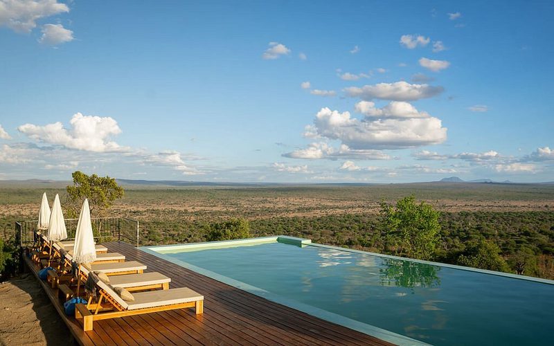 Piscina infinita de la Mwamba Lodge Tarangire con tumbonas sobre una amplia llanura de matorral