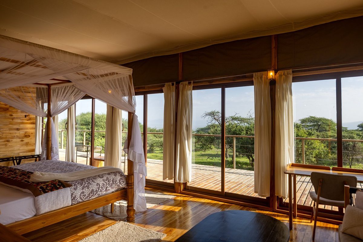 Zeltzimmer im Naserian Safari Camp mit Himmelbett und großer Glasfront zur Holzterrasse