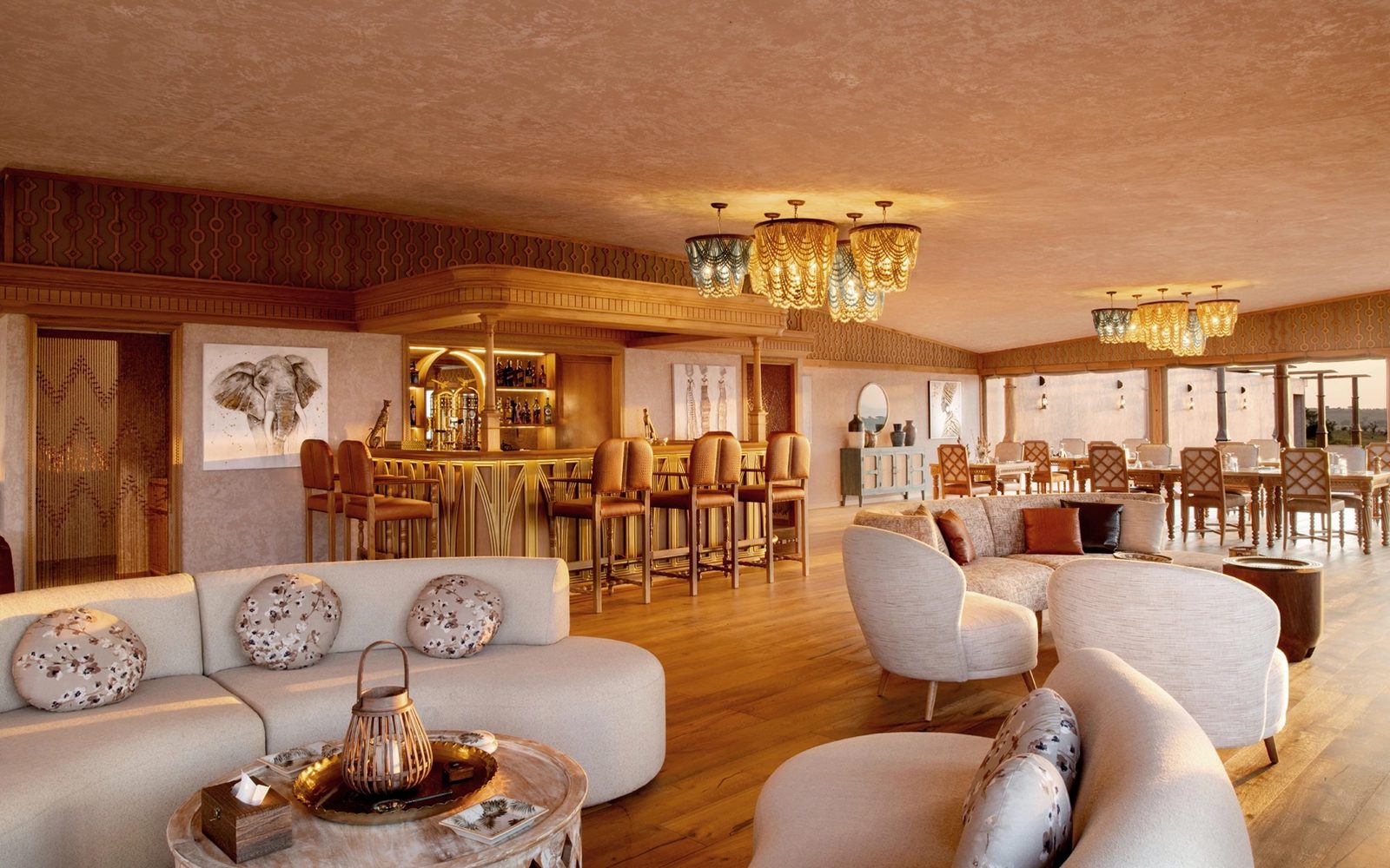Salón de One Nature Mara River con sofás claros y bar con luz cálida