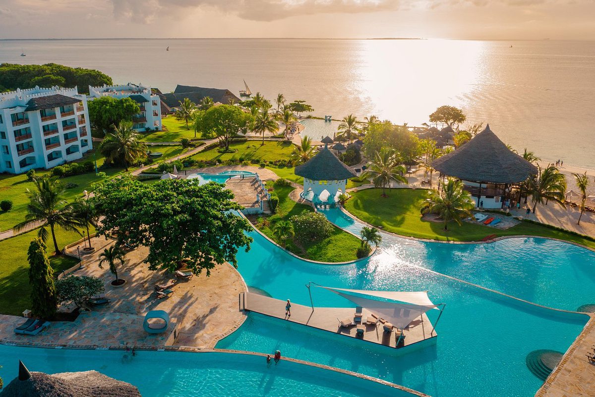 Zona de piscinas del Royal Zanzibar Beach Resort con pabellones y edificios del hotel junto al mar al atardecer