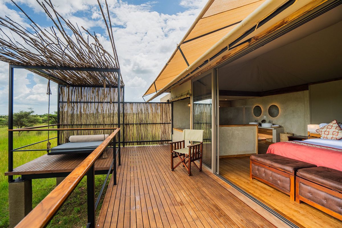 Terraza de madera de una habitación de la tienda de Salinero Serengeti con cama de día y vistas al pastizal
