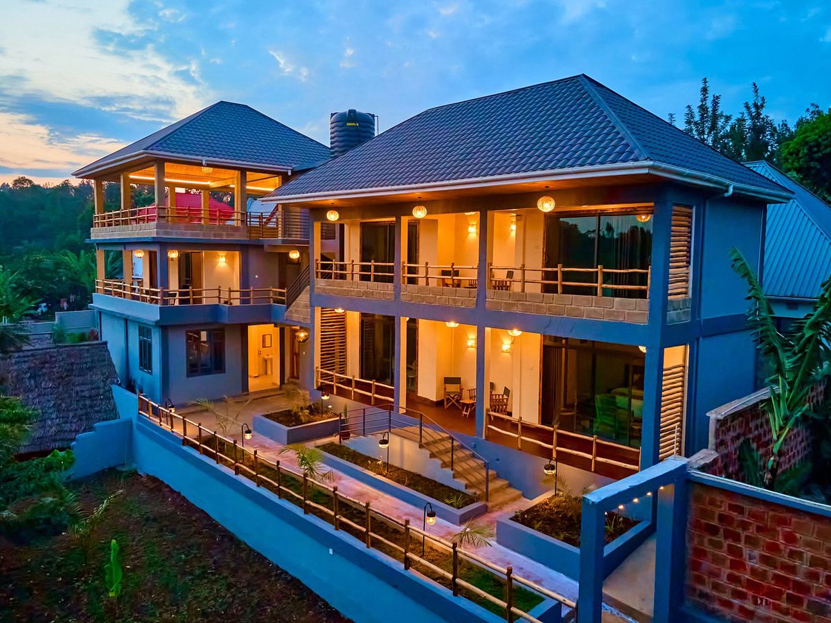 Edificio de dos plantas de la Samora River Lodge con balcones de madera iluminado al anochecer