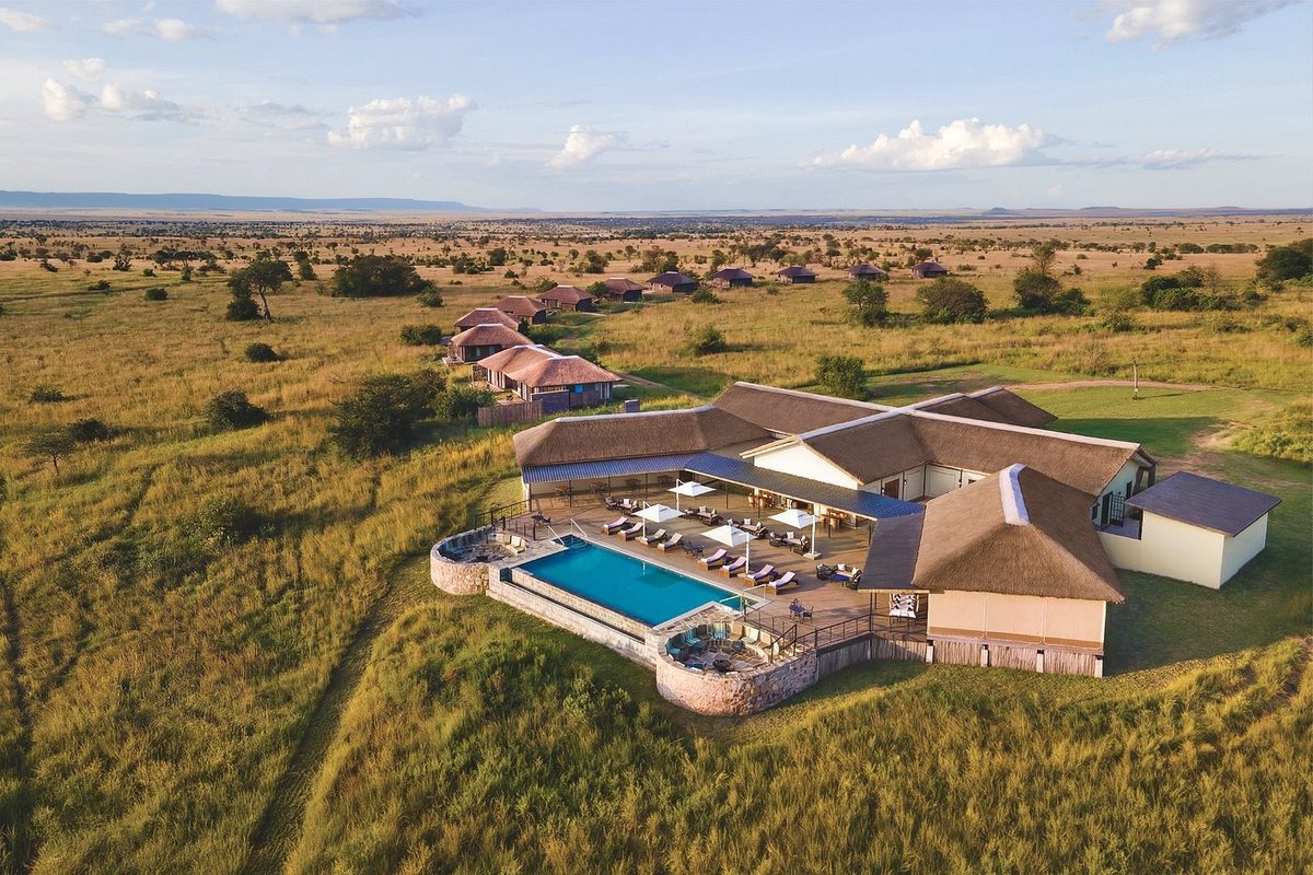 Serengeti Mara River Camp desde el aire con techos de paja, piscina infinita y sabana hasta el horizonte