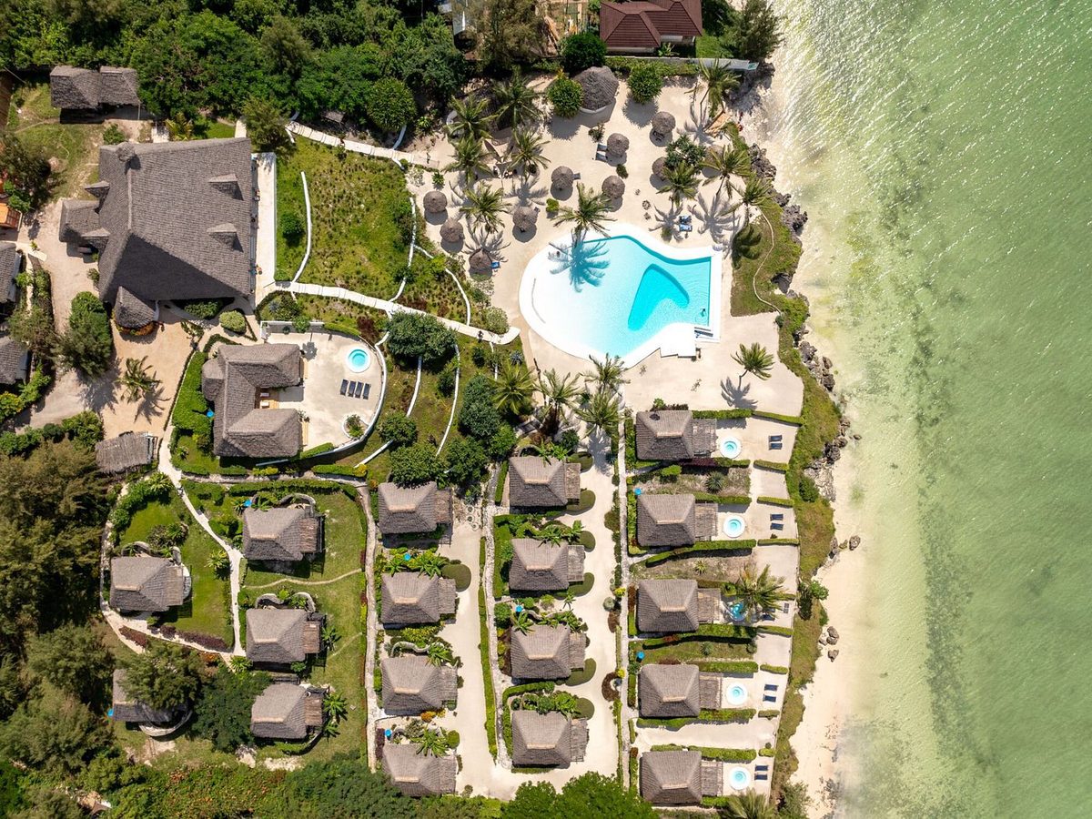 Complejo del Zanbluu Beach Hotel con piscina y bungalows con techos de paja en la costa desde arriba