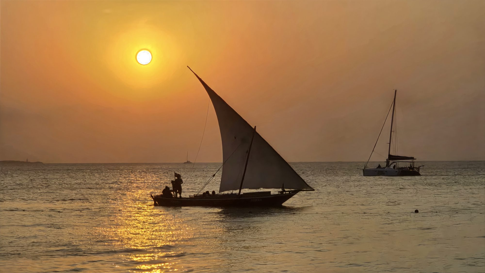 Vela de un dhow contra el sol bajo, frente a Zanzíbar