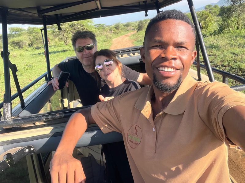 Guide macht ein Selfie mit zwei Gästen im Safarifahrzeug