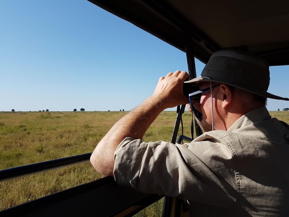 Safari-Gast mit Fernglas – authentische Erfahrungsberichte über Safari-Abenteuer in Tansania