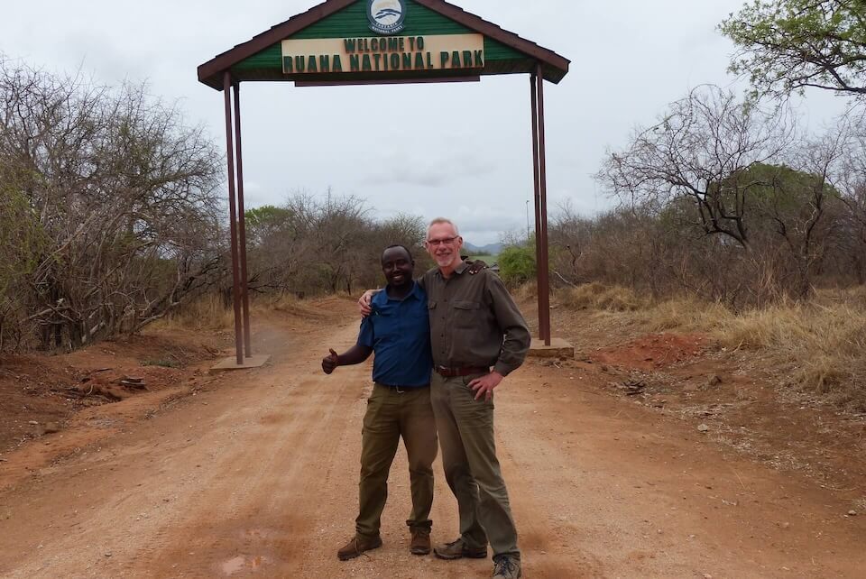 Safari-Gast mit Guide am Tor des Ruaha Nationalparks – Start in ein authentisches Tansania-Abenteuer